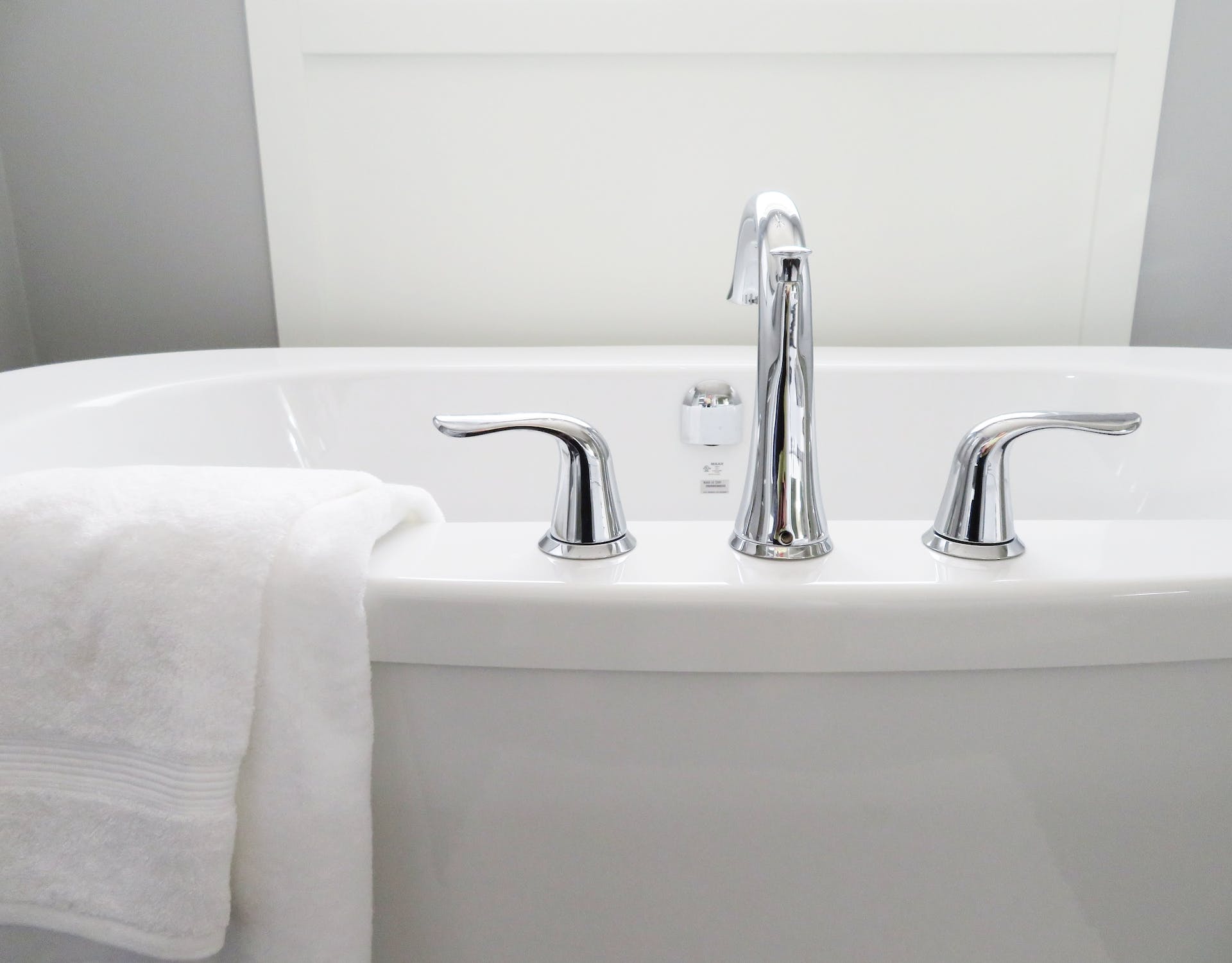 White towel hung on white bathtub; image by Pixabay, via Pexels.com.